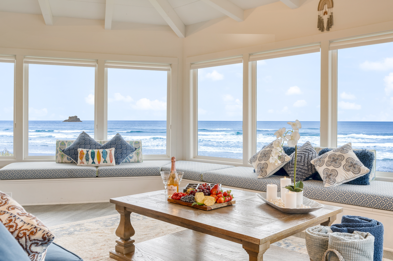 big windows of a house living room facing the blue ocean waves