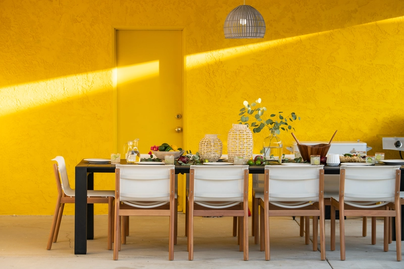 yellow wall with a black long wood table for 8 seating