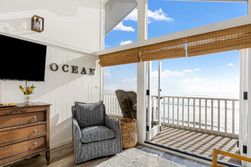 cozy gray sofa by the balcony with a view of the sea and wall design spelling out ocean