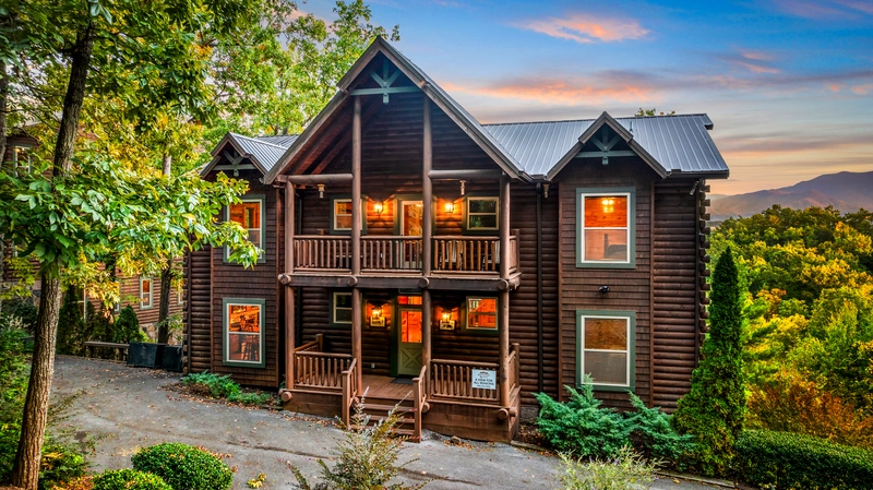 brown log cabin with lights from the inside showing on the windows making it the best smoky mountains airbnb