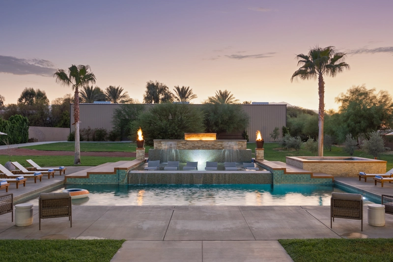 resort style pool with 2 fire pit columns and a waterfall as one of the best Coachella Airbnb