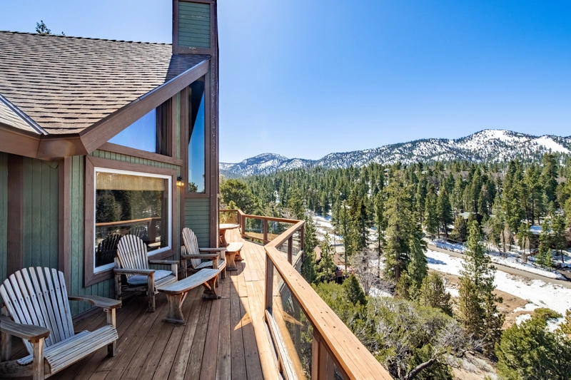 wood deck balcony overlooking the forest evergreen trees with snowcaps making it the best big bear airbnb