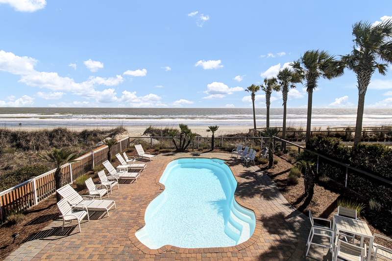 big oasis swimming pool fronting the beach with palm trees making it the best isle of palms airbnb