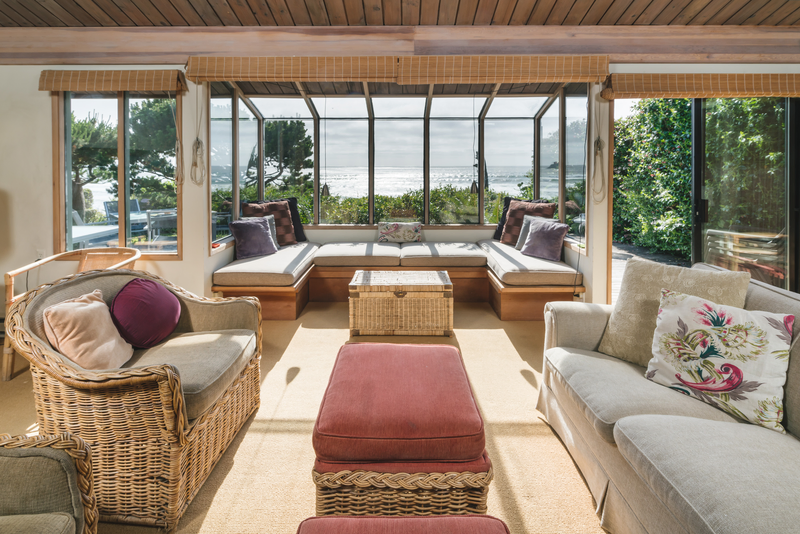 big paneled window with seating facing the ocean during sunset