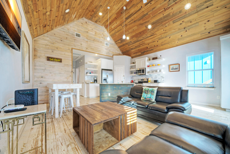 living area with black leather sofa and vaulted wood ceiling making it the best corpus christi airbnb