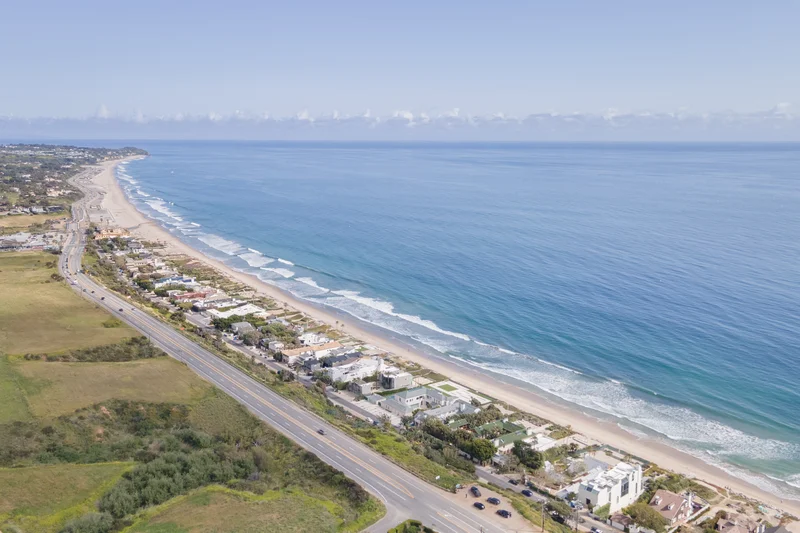 eagle view of the vast blue ocean of Malibu and coastal houses by the highway