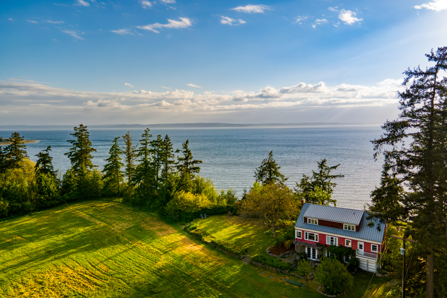 red barn house by the forest of pine trees grass and big blue lake