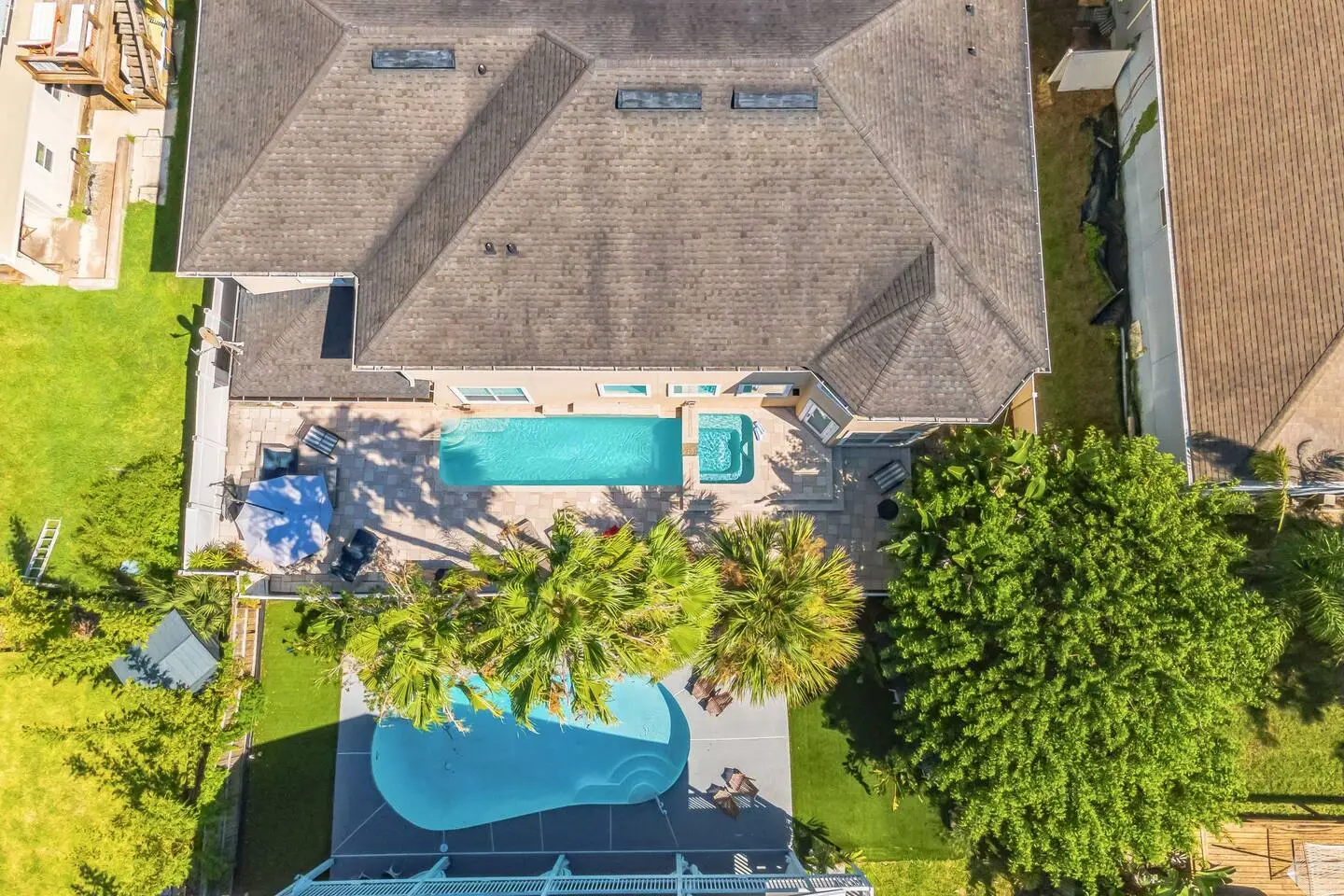 overhead shot of a mansion house with two big swimming pools at the backyard