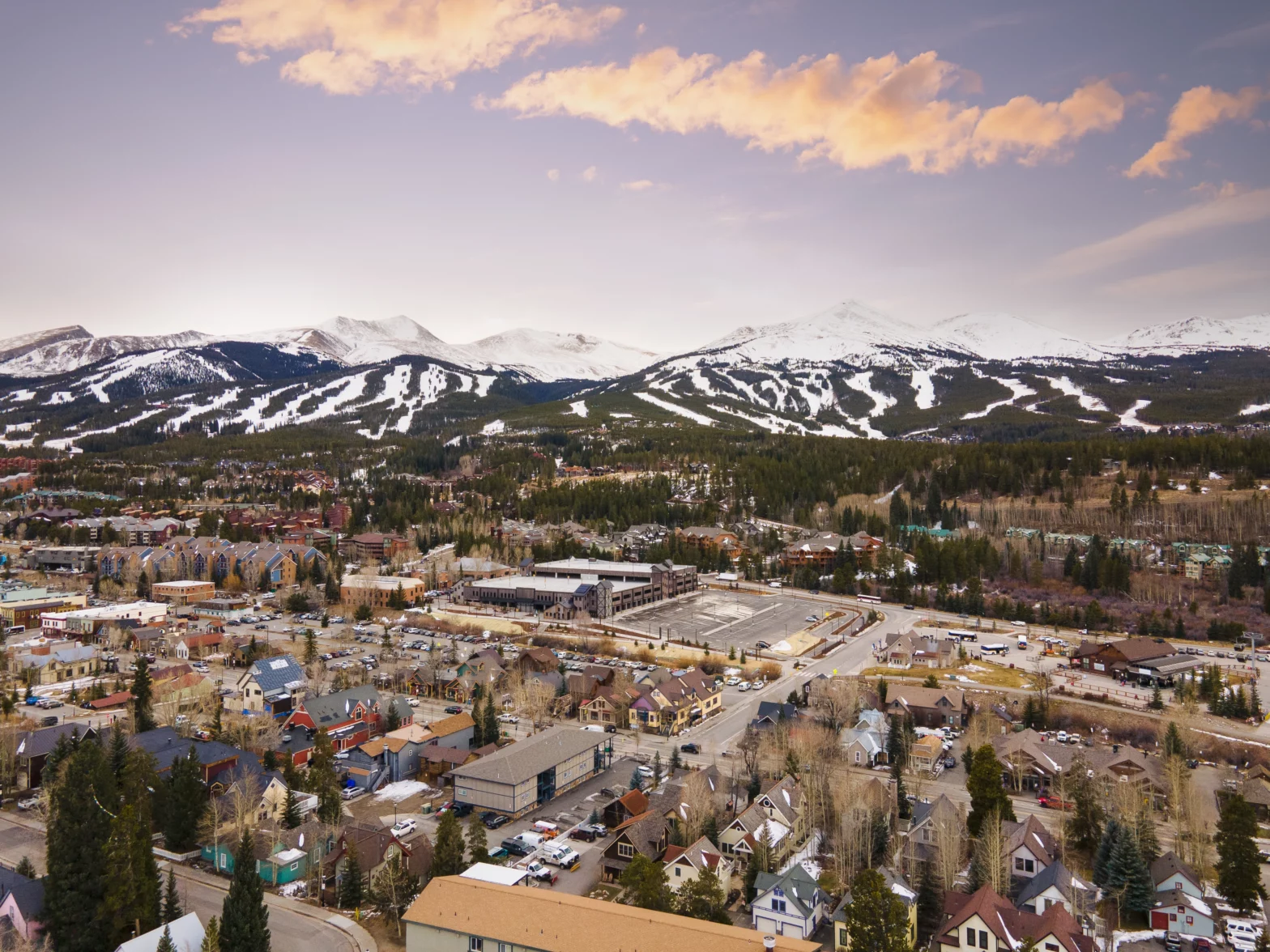 overhead view of the city with a snow capped mountains during a sunset