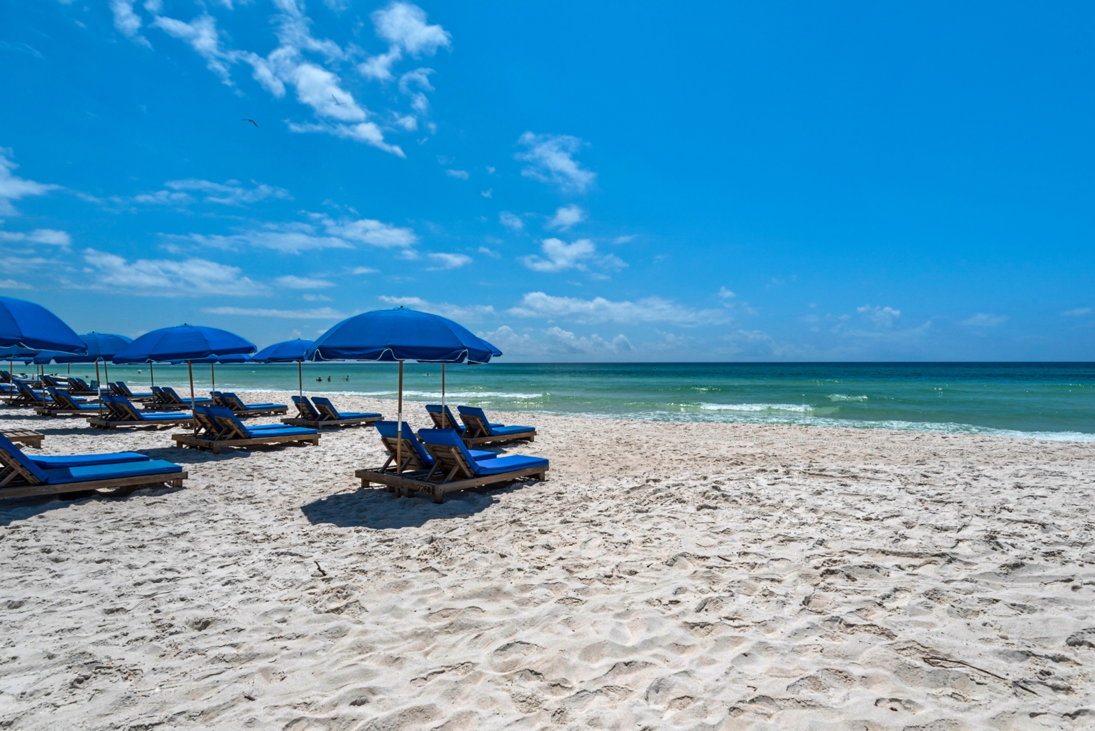 torquise blue beach and white fine sands of panama city beach with beach chairs and umbrellas