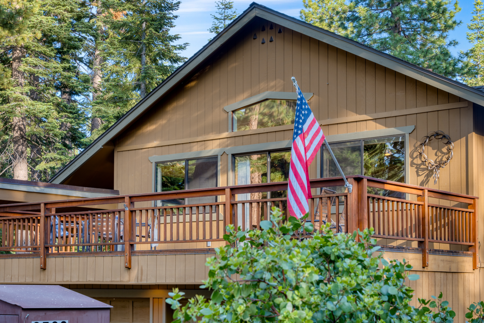 exterior of a wood house with a wood deck balcony and a flag pole