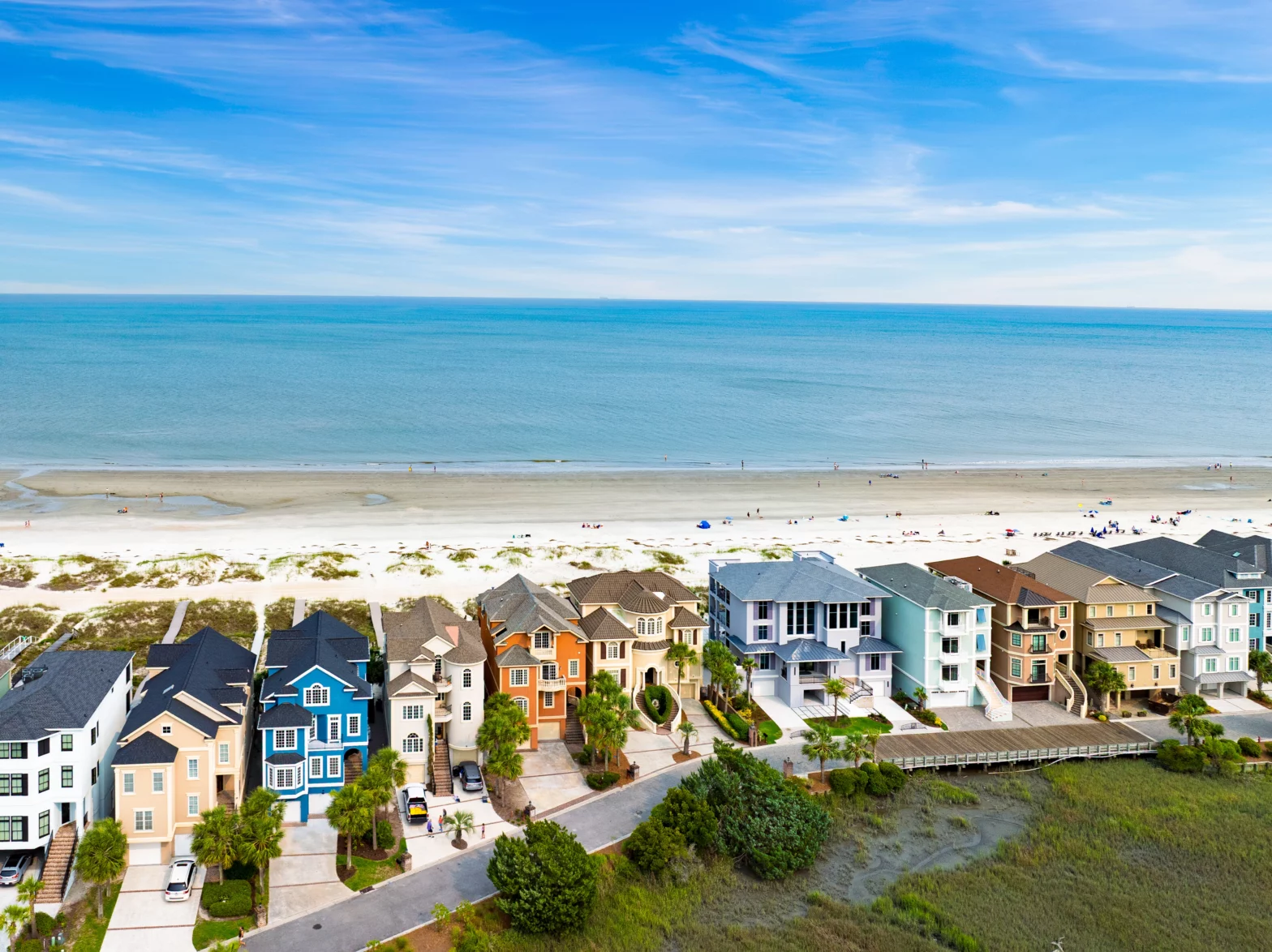 multi colored beach houses by the blue turquoise sea and white sand