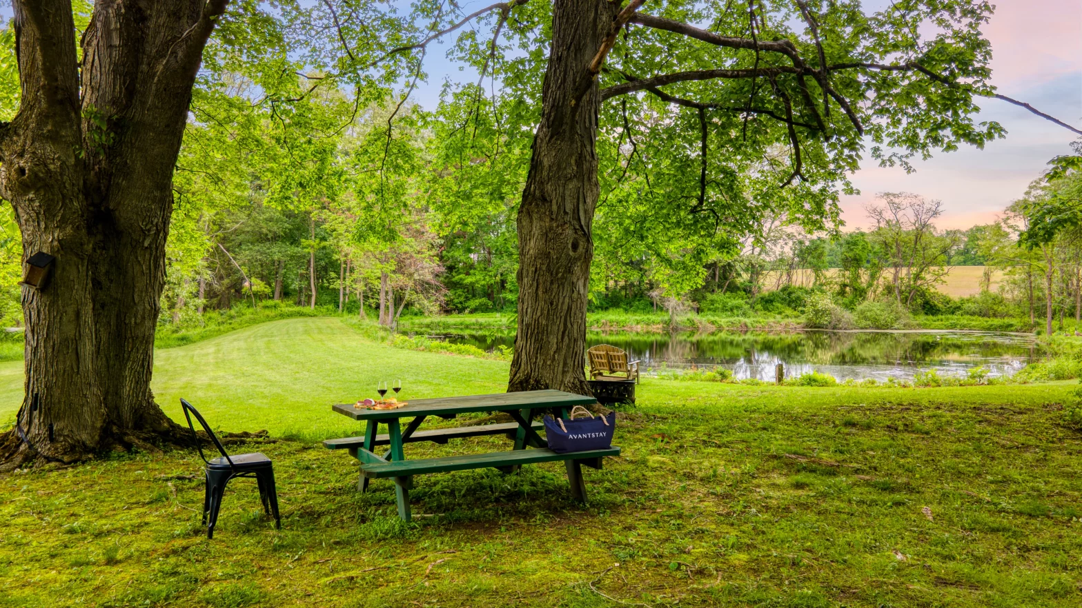 mossy wood picnic table under the shade of a green big tree by the black pond