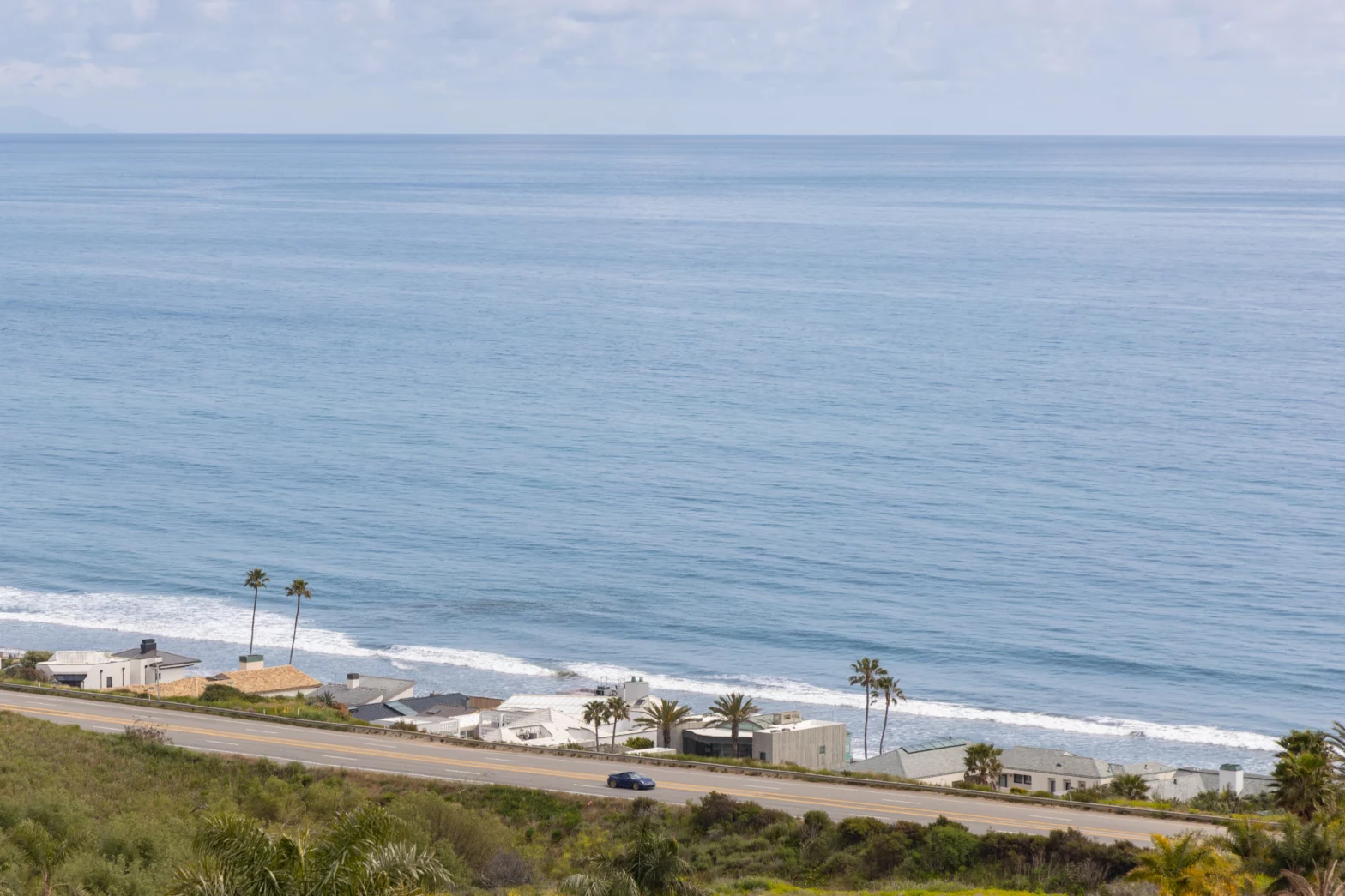 eagle view of the Pacific sea and waves with beach and road side homes
