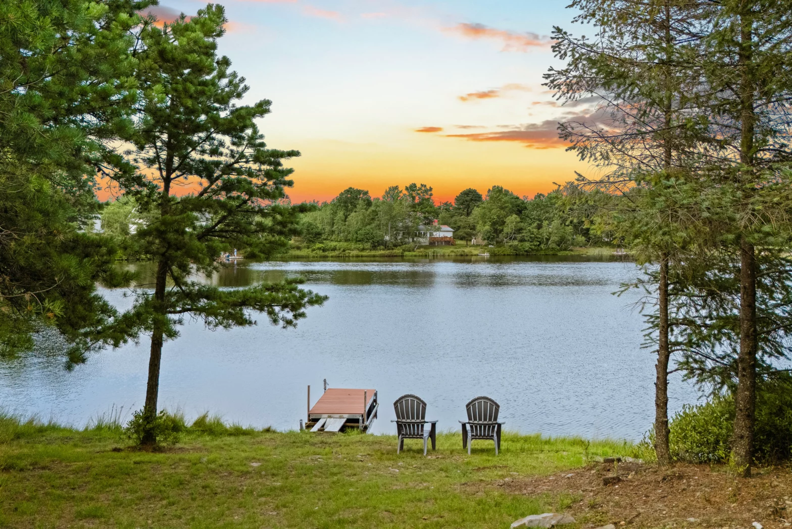 two plastic chairs faced on the black big lake watching over the orange sunset