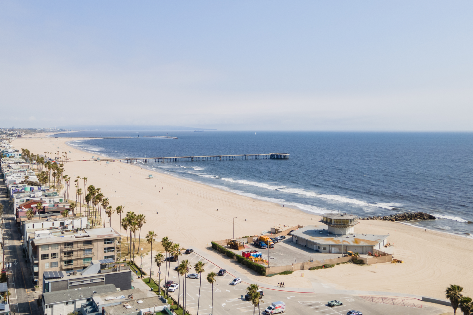 overview shot of the white beach and blue waves along a line of palm trees