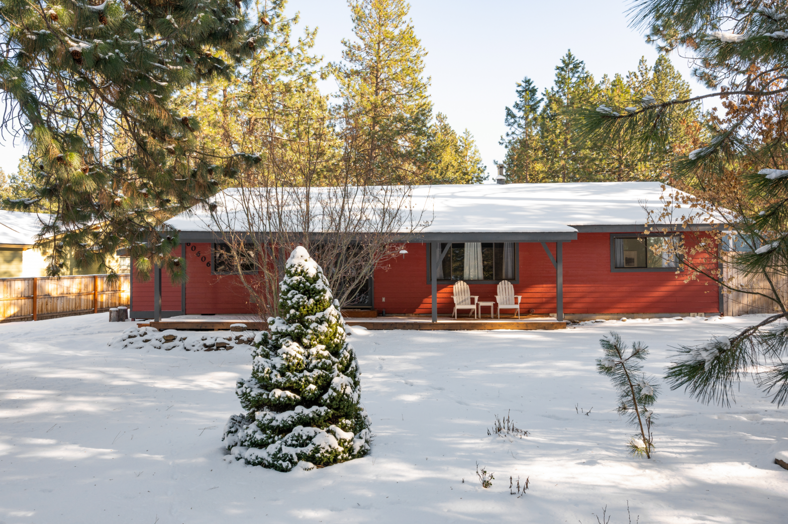 red log cabin surrounded by snow and dusted green pine trees