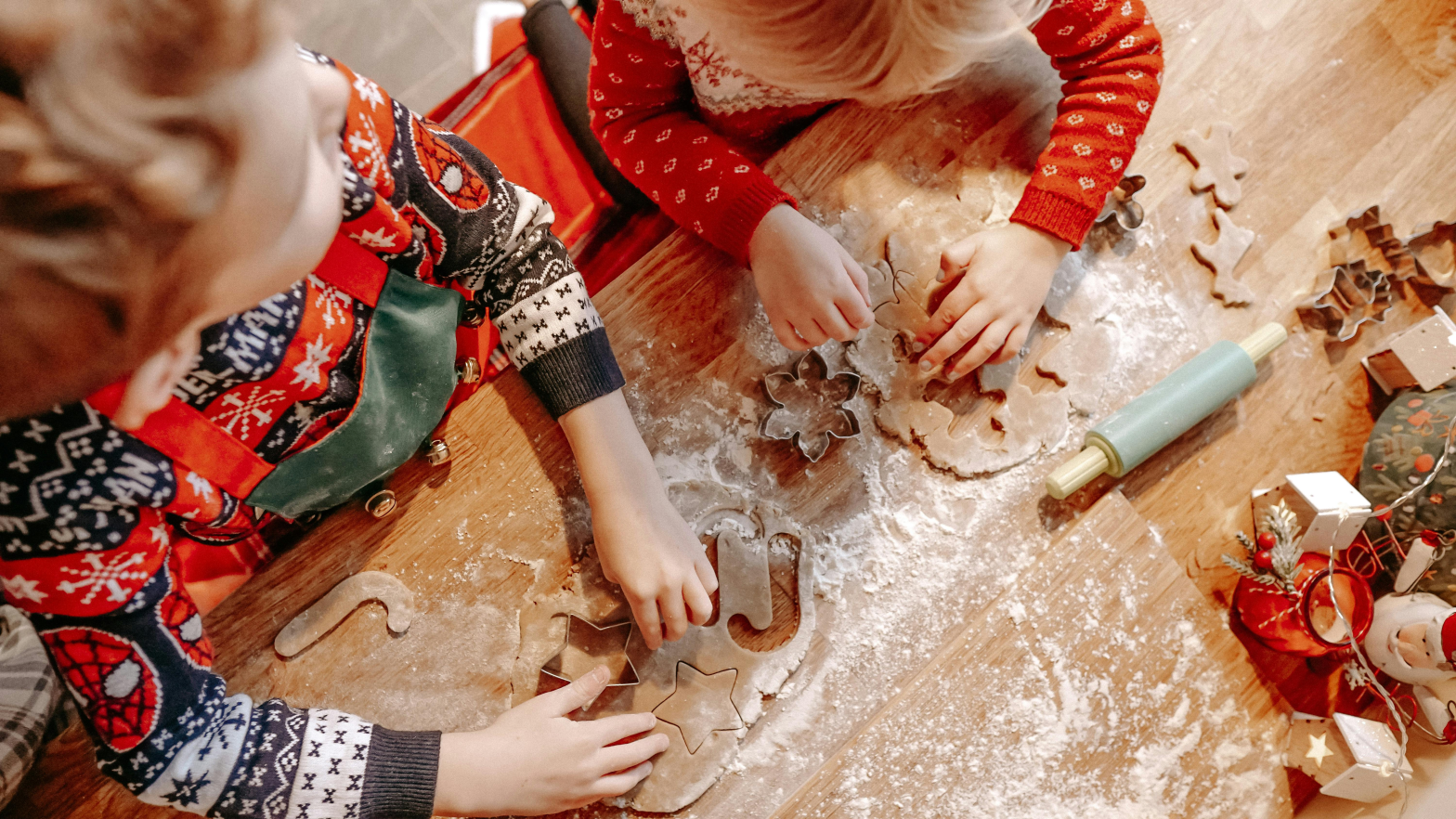 2 pairs of toddler hands baking a cookie and gingerbread man with flour and rolling pin