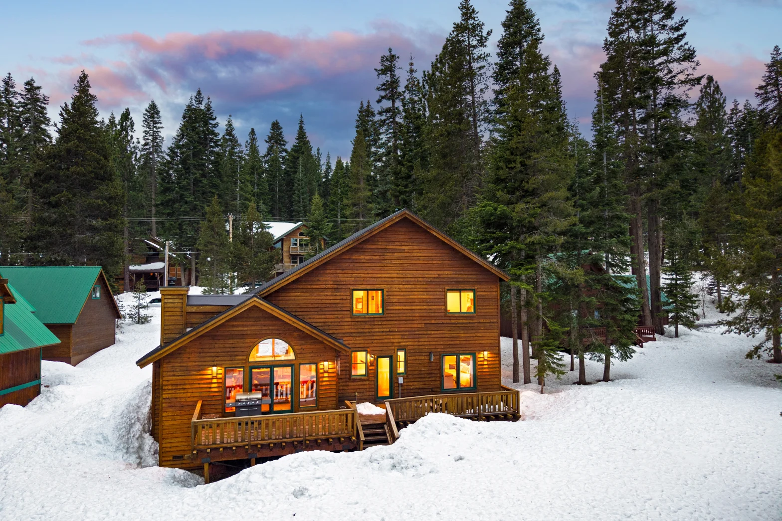 outdoor shot of a wood log cabin burried in white snow and surrounded by green pines
